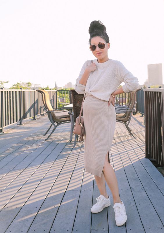 A ribbed knit skirt paired with a cropped or knotted sweater creates a stylish yet comfortable maternity outfit. The fitted skirt highlights the bump, while the relaxed top keeps things effortless. Sneakers and a crossbody bag complete this casual-chic look.