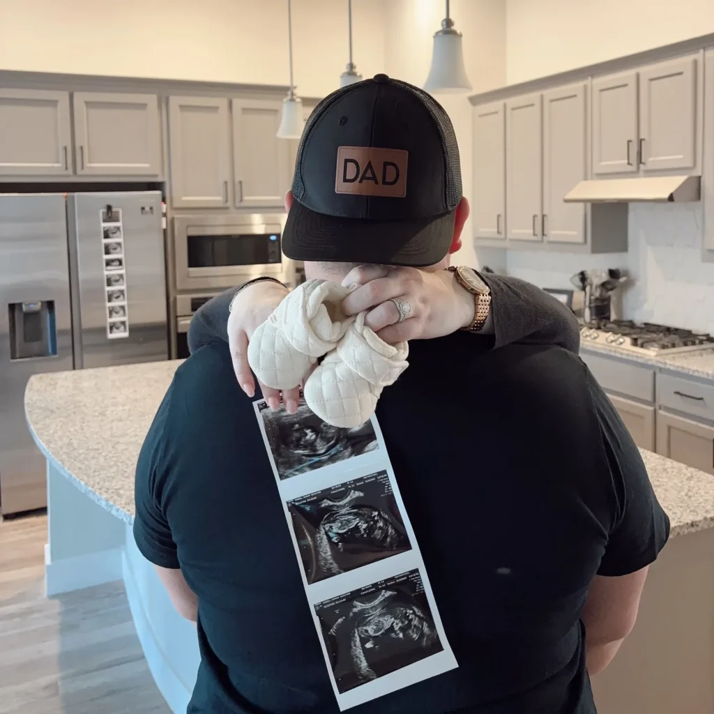 A sweet and simple way to announce the big news! A "DAD" hat, baby booties, and ultrasound photos make this a heartfelt and memorable reveal.