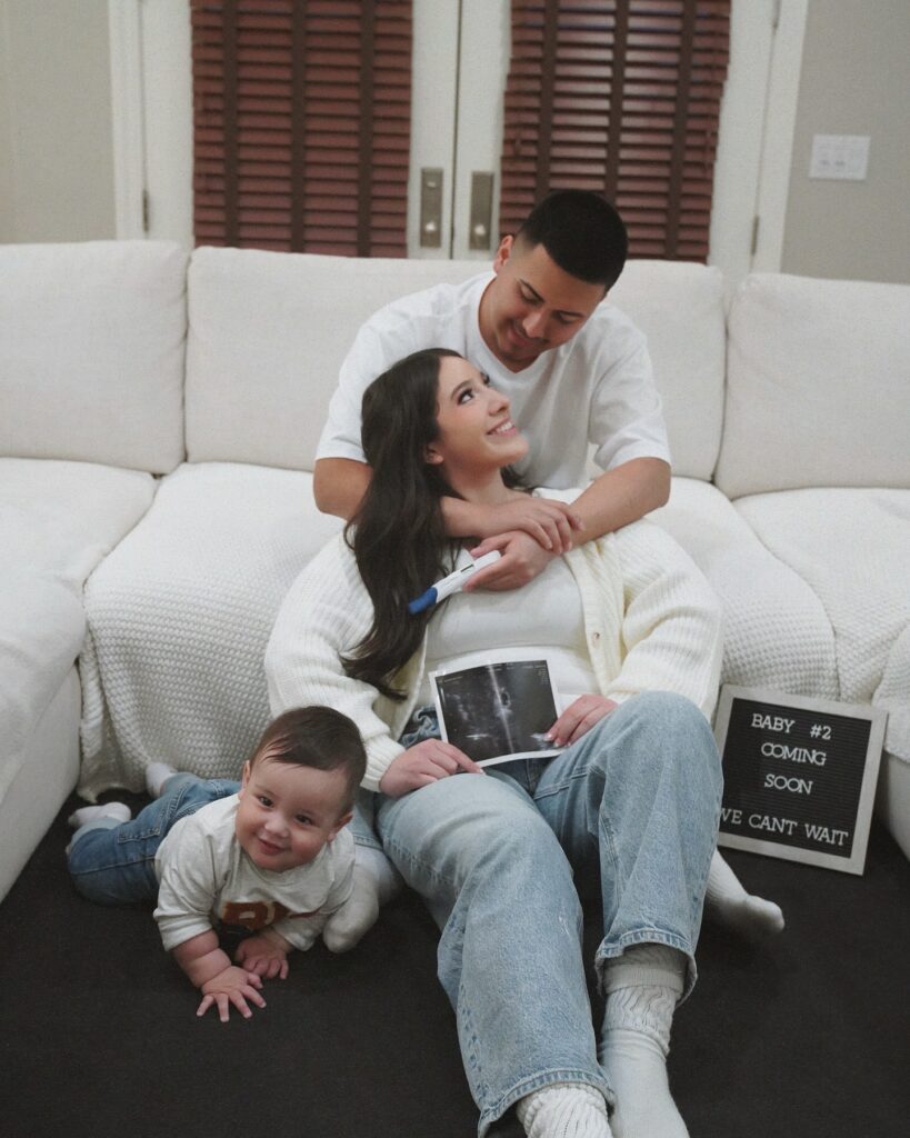 a man and woman sitting on the floor with a baby and ultrasound