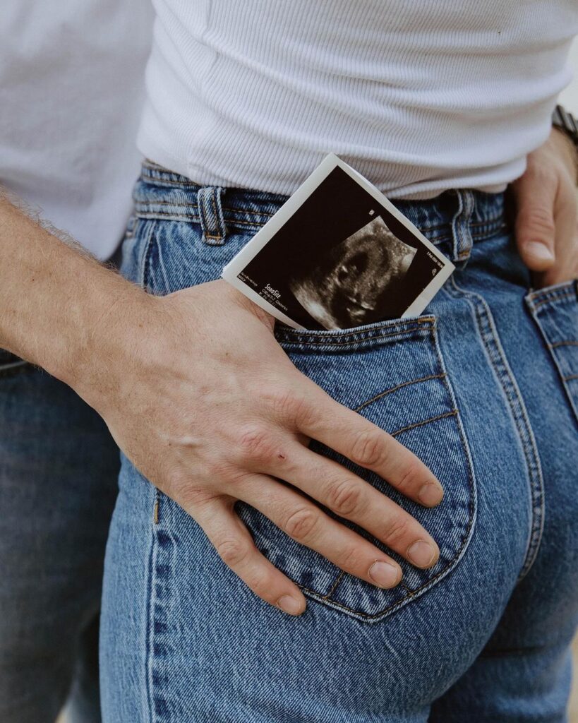A Women holding an ultrasound picture in their jeans pocket
